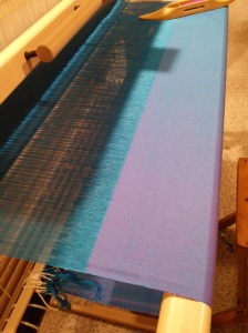 Sighting along the iridescent silk cloth, the near surface is violet while the far end is mostly blue.